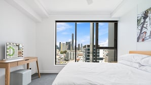 Une chambre d’hôtel moderne avec un grand lit, un bureau donnant sur la ville et une grande fenêtre.
