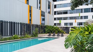 Un bâtiment moderne doté d’une piscine, d’un espace extérieur aménagé et d’une végétation luxuriante.