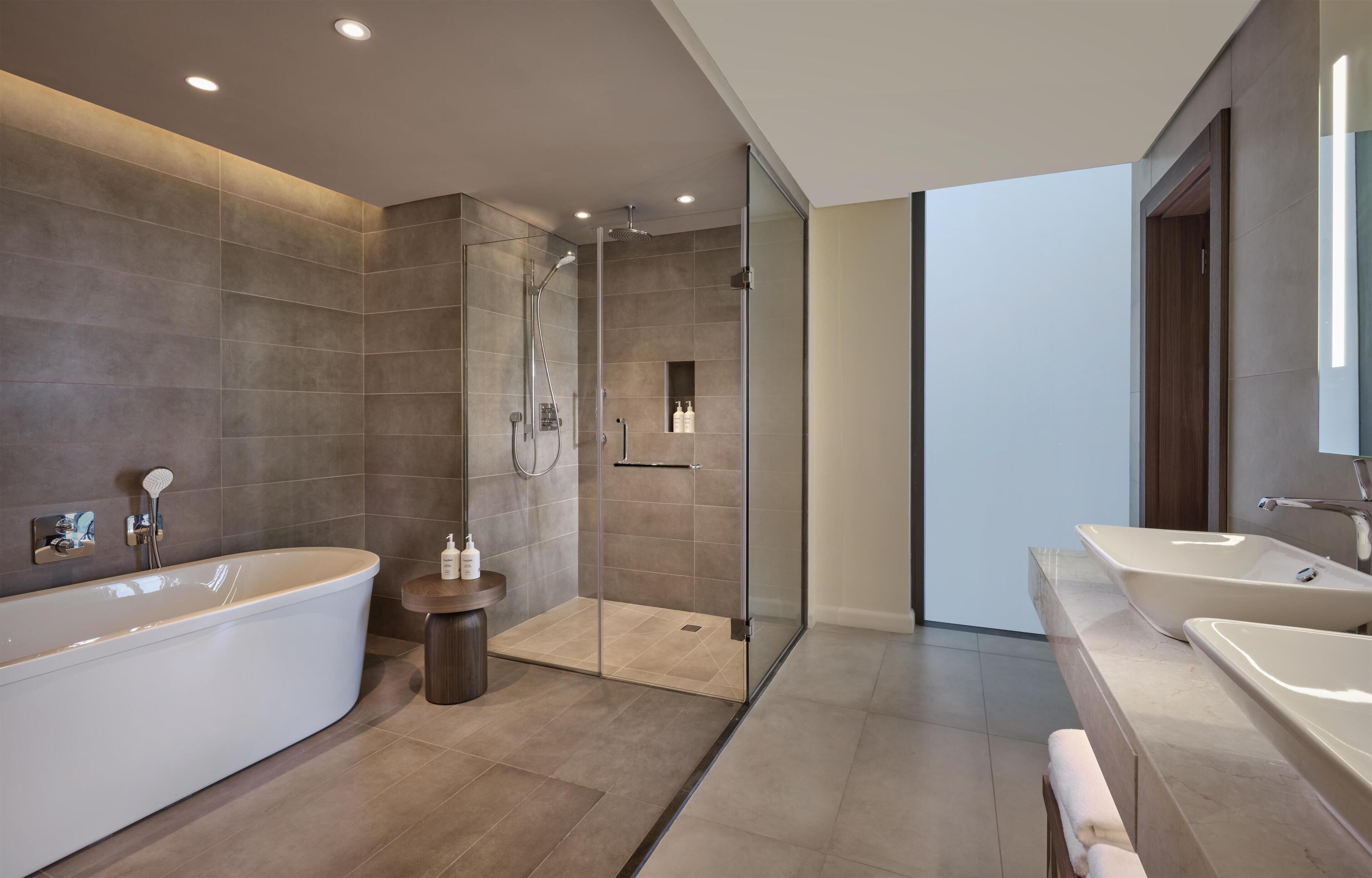 A modern bathroom with a freestanding bathtub, a glass-enclosed shower, and a vanity with two sinks.