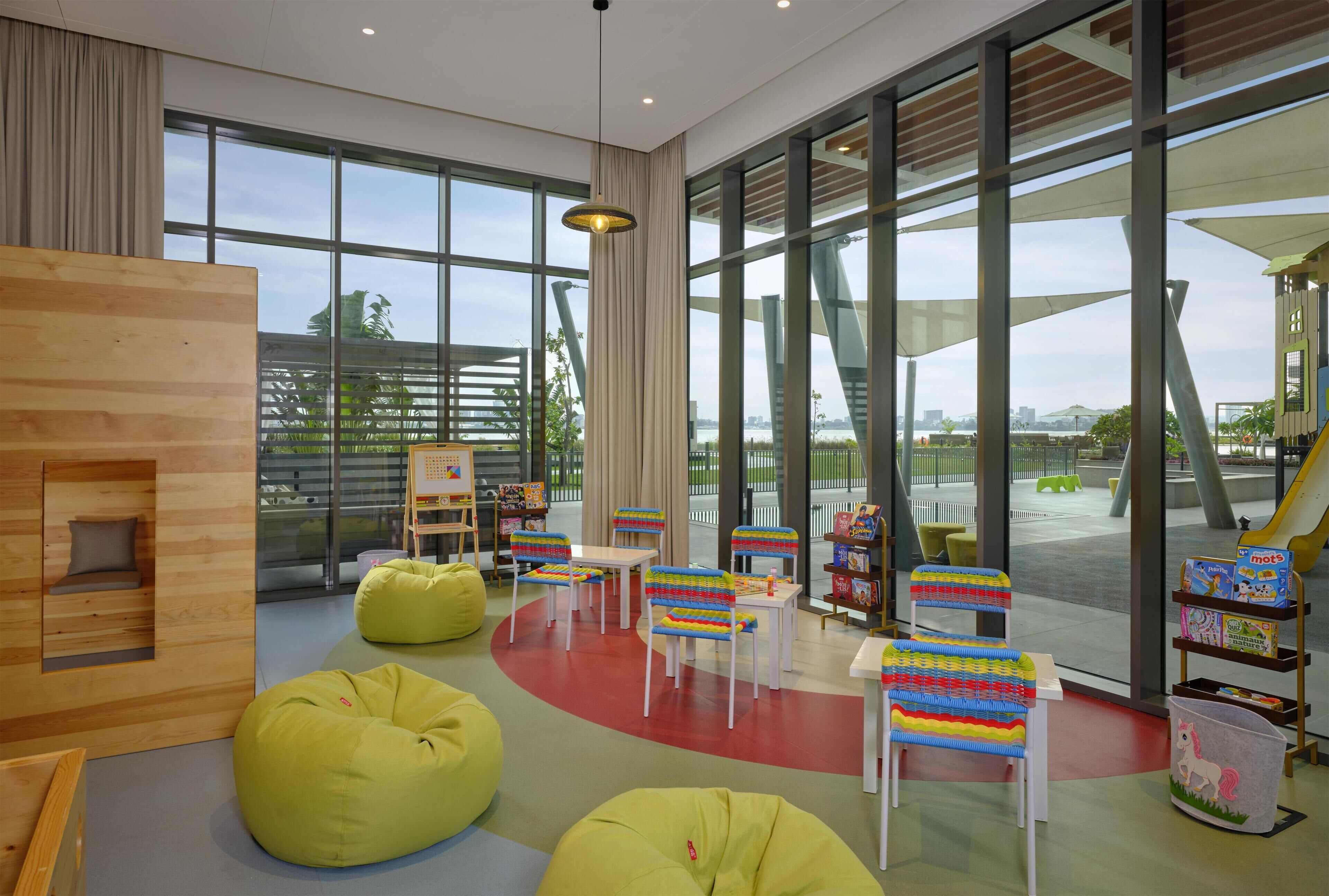 A children's play area with bean bags, colorful chairs, and a view of the outside.