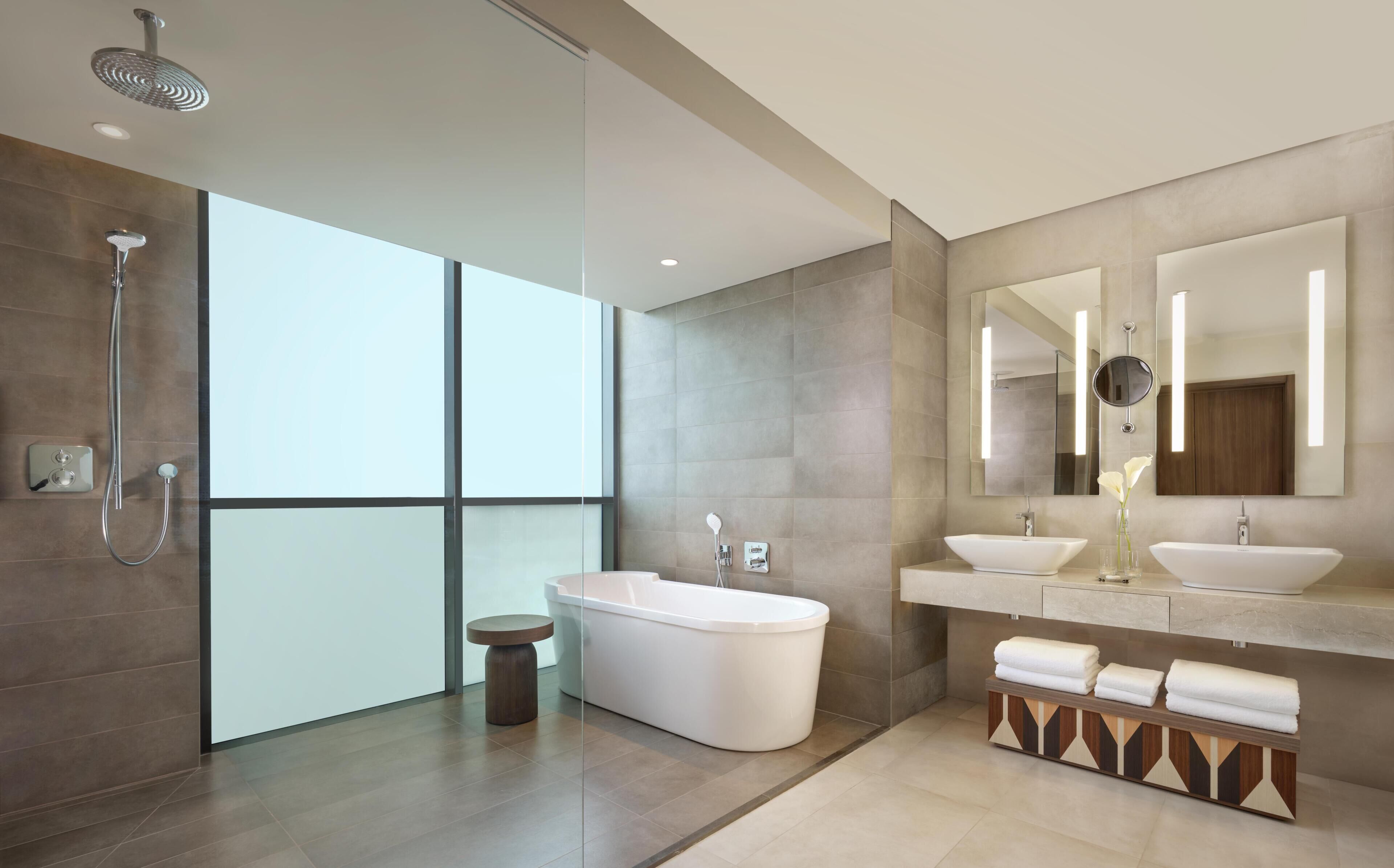 Une salle de bain moderne avec une baignoire sur pieds, un grand miroir et une pomme de douche.