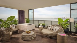 Un balcon agrémenté de meubles en osier, un jacuzzi et une vue sur la mer.