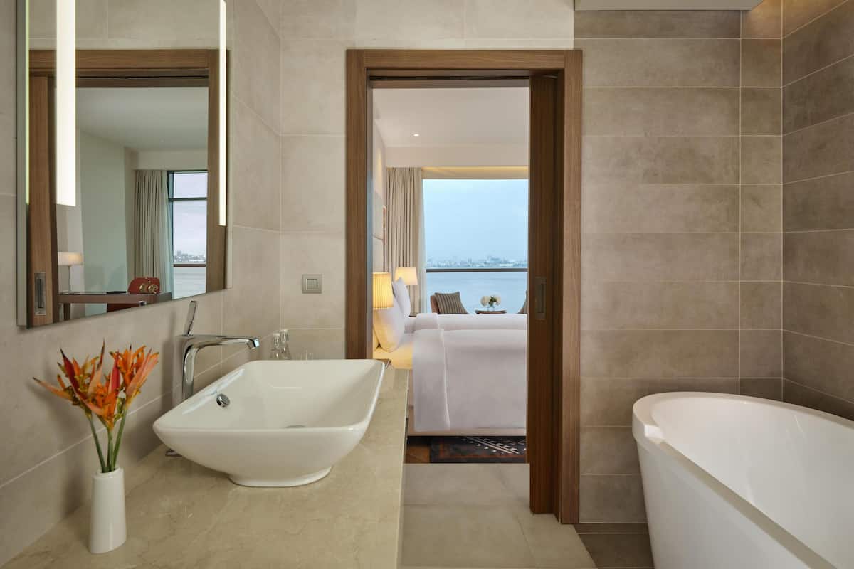 A modern bathroom with a freestanding bathtub, a large mirror, and a vase with flowers.