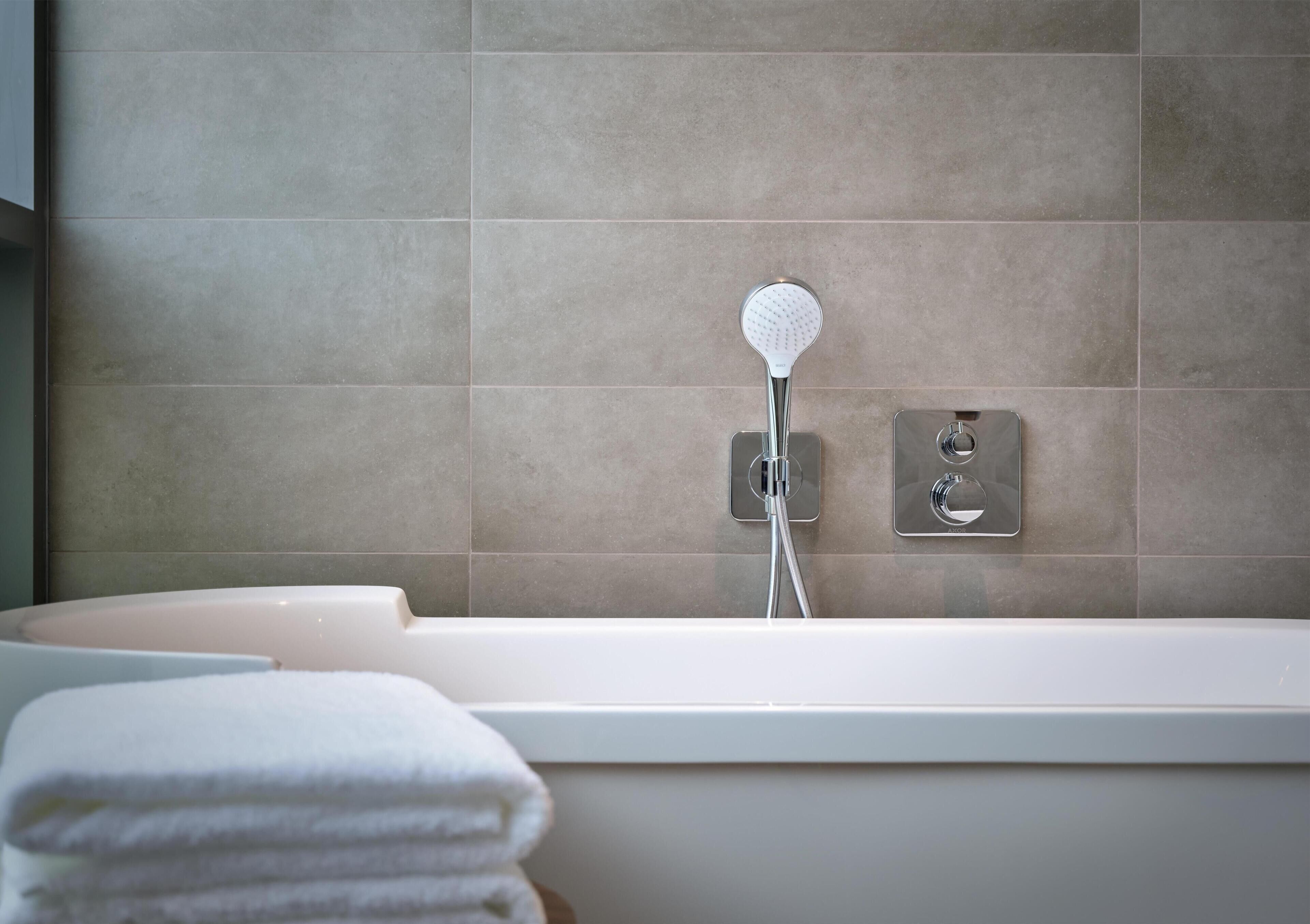 Een moderne badkamer met een bad, douchetuit en een handdoekhouder.