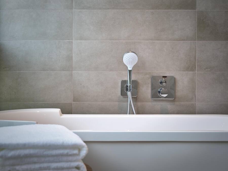Een moderne badkamer met een bad, douchetuit en een handdoekhouder.