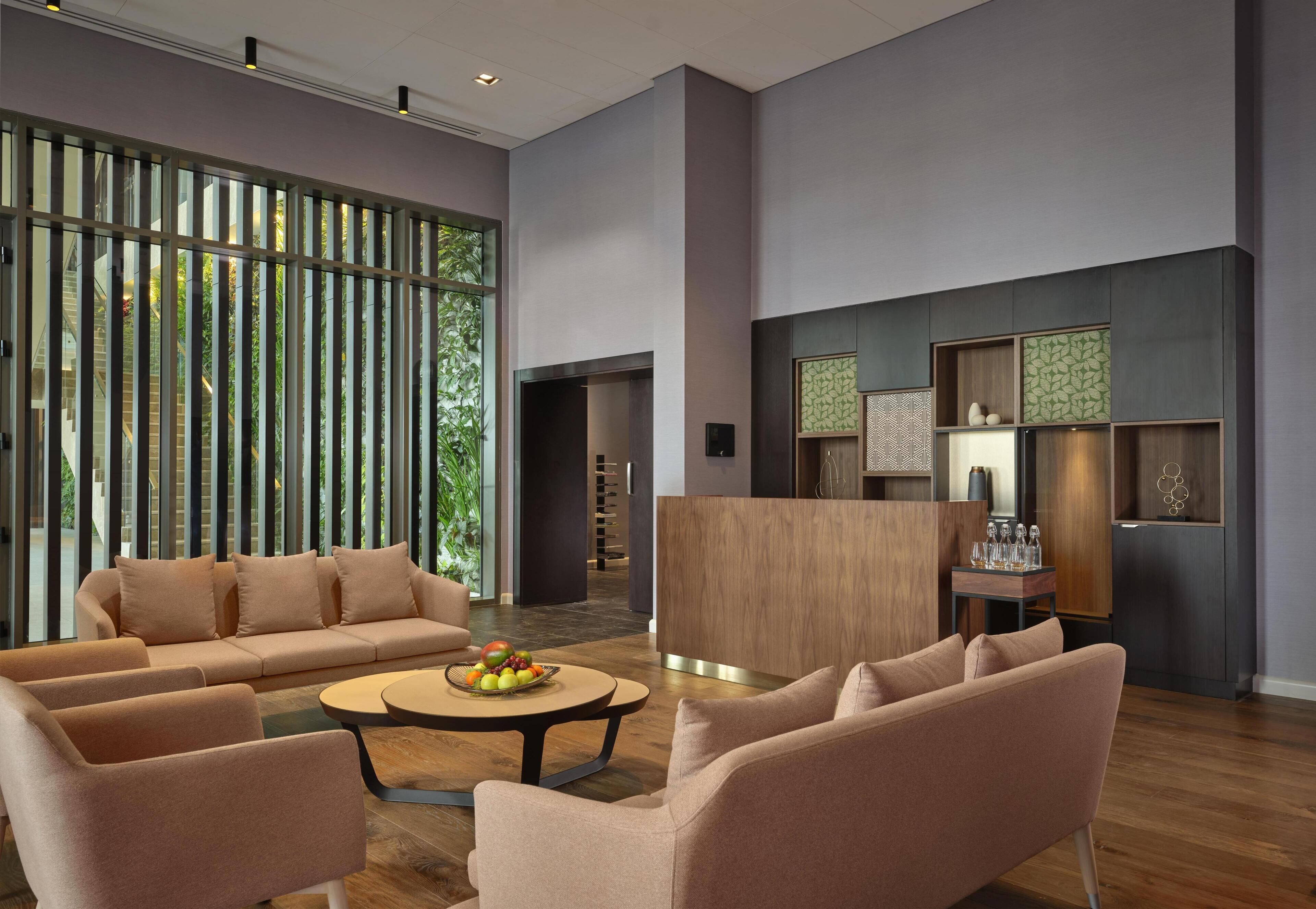 A spacious lobby with a sofa set, a coffee table with fruit, and a reception desk.