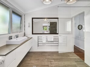 A modern bathroom with a large mirror, white fixtures, and a wooden floor. - Riverside 3-bed Townhouse With Spacious Deck & BBQ (Mossy Point)