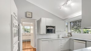 A modern kitchen with white cabinetry, a built-in microwave, and a wooden floor. - Riverside 3-bed Townhouse With Spacious Deck & BBQ (Mossy Point)