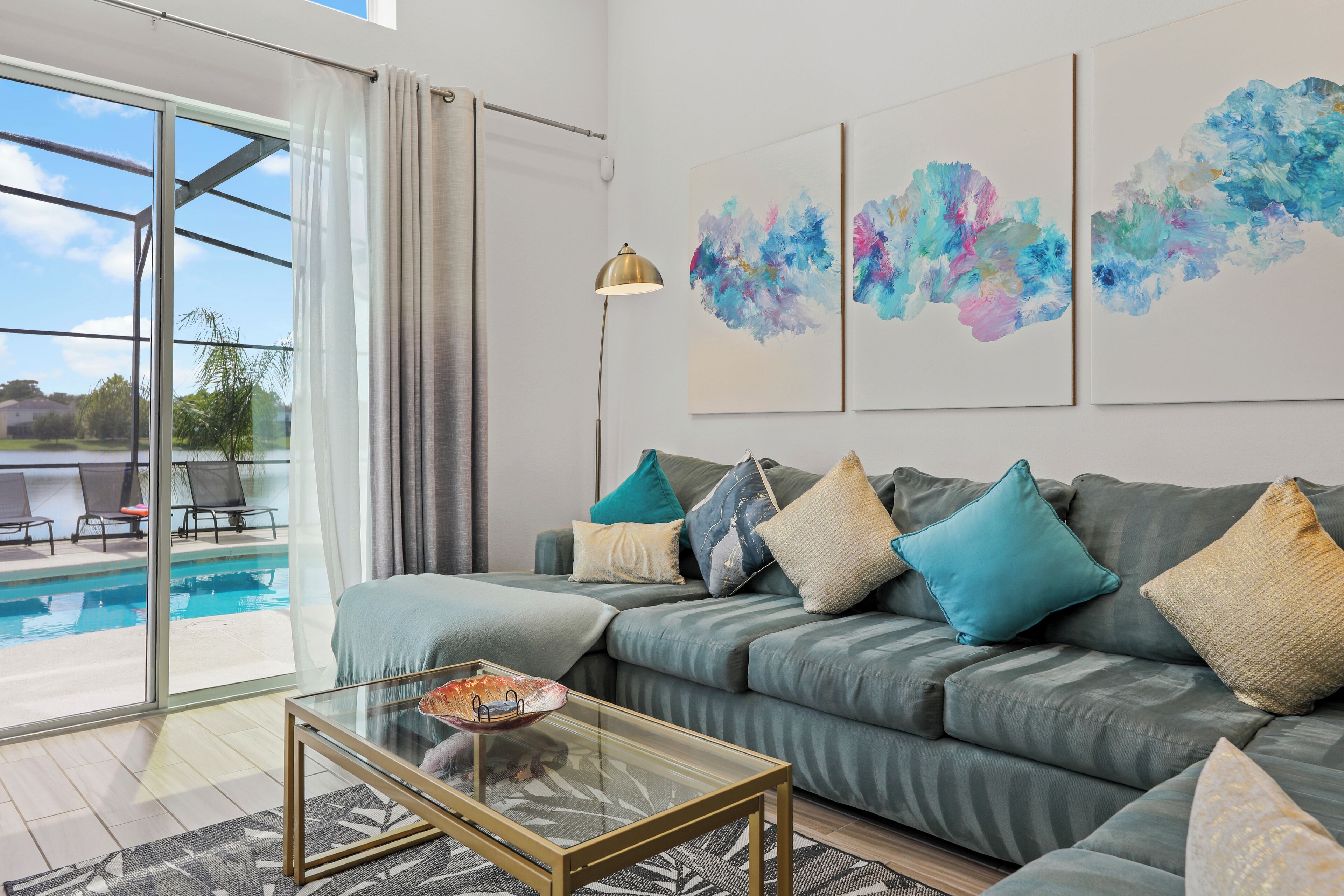 Ein modernes Wohnzimmer mit grauem Sofa, einem Glastisch und abstrakter Kunst an der Wand.