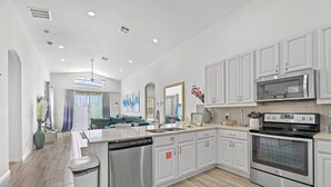 A modern kitchen with white cabinets, stainless steel appliances, and a central island. - 4BR Retreat, Pool, Close to Disney (Kissimmee)