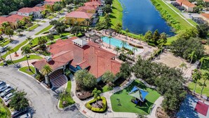An aerial view of a residential area with houses, a swimming pool, and a river. - 4BR Retreat, Pool, Close to Disney (Kissimmee)