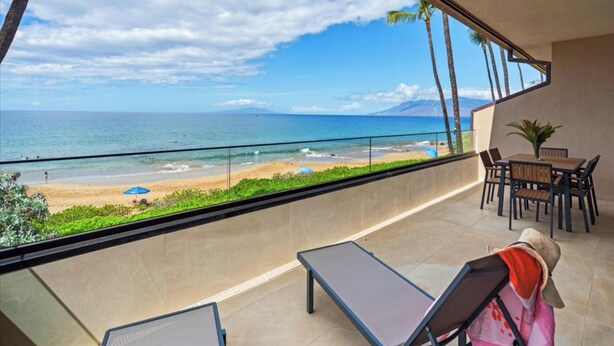 A balcony with a view of the beach and ocean. There are lounge chairs and a table with chairs. - Makena Surf B201 | 2nd Floor Oceanfront, On the Beach & Turtle Reef (Wailea)