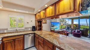 Una cocina con armarios de madera, encimeras de granito, lavavajillas y una isla grande.