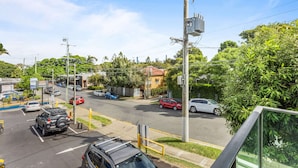 A street view with cars parked along the side, a clear sky, and greenery. - Spacious and Superb 3-bed Apartment (Brisbane)