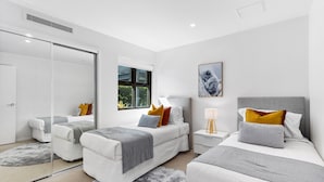 A modern bedroom with two beds, a large window, and a mirror. - Spacious and Superb 3-bed Apartment (Brisbane)