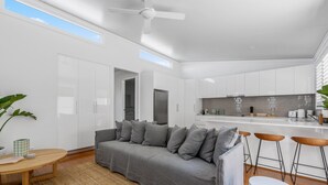 A modern living room with a grey sofa, wooden coffee table, and a ceiling fan. - Relaxing 2-bed Home Close to Beaches and Parks (Sydney)