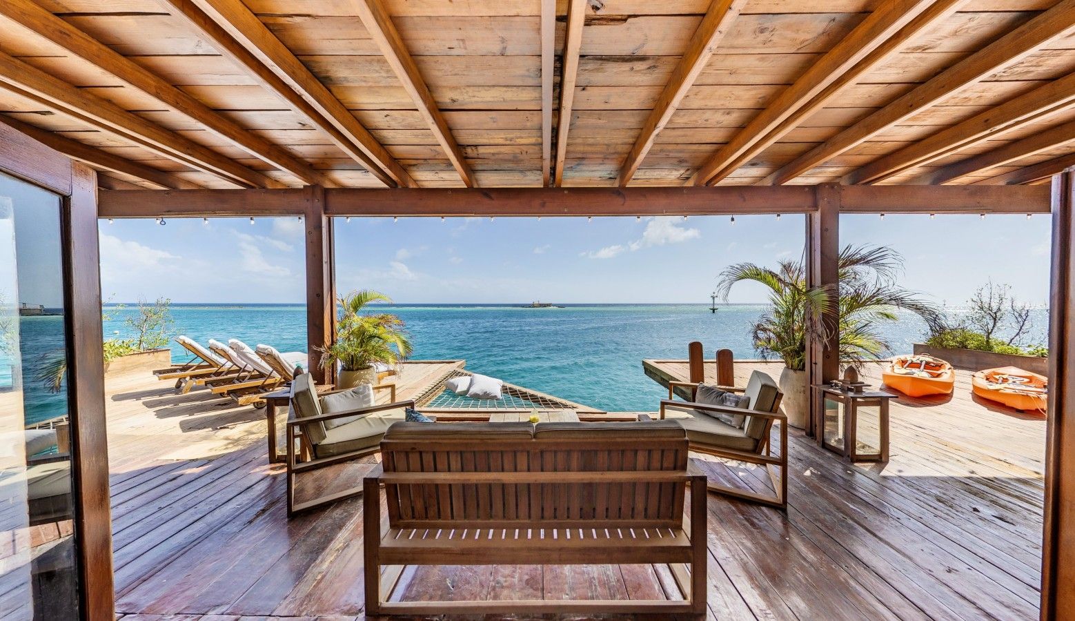 Une terrasse extérieure avec des meubles en bois et une vue sur l’océan.