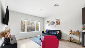 Una sala de estar moderna con un sofá negro, un sillón rojo y un mueble de entretenimiento negro.