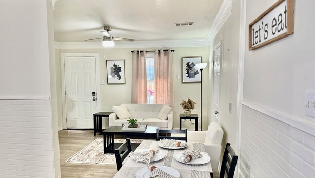 A dining area with a table set for four, a ceiling fan, and a 'Let's eat' sign on the wall. - 3 BR Home Near Airport & Downtown (Austin)