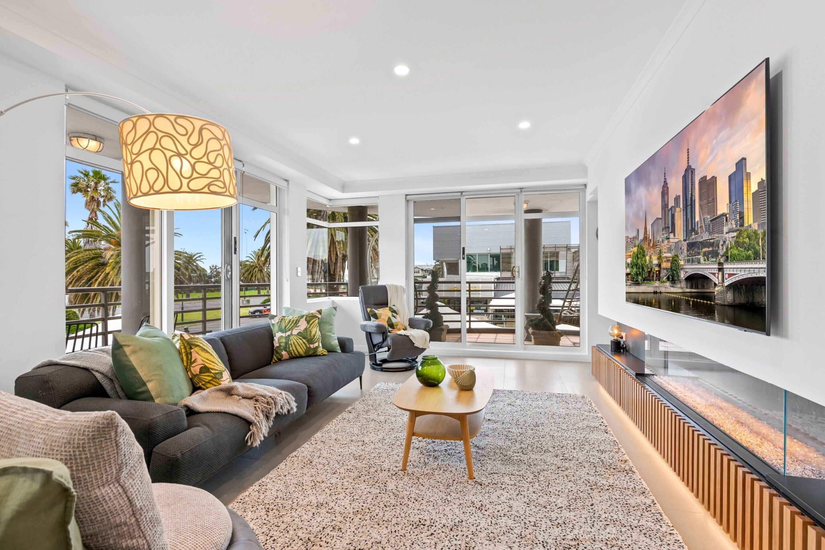 A modern living room with a sofa, coffee table, and a large TV on the wall.