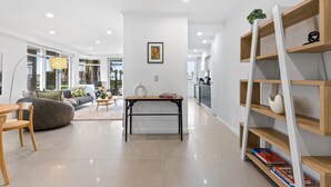 A modern living room with a sofa, coffee table, and a bookshelf. - Scenic Beachside 3-bedroom With Water Views (Melbourne)
