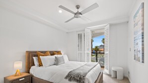 A bedroom with a bed, nightstand, and ceiling fan. - Scenic Beachside 3-bedroom With Water Views (Melbourne)