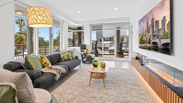 A modern living room with a sofa, coffee table, and a large TV on the wall. - Scenic Beachside 3-bedroom With Water Views (Melbourne)