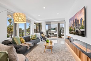 Un salon moderne avec un canapé, une table basse et un grand téléviseur fixé au mur.