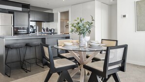 Cozinha moderna com ilha central, banquetas e mesa de jantar com cadeiras.