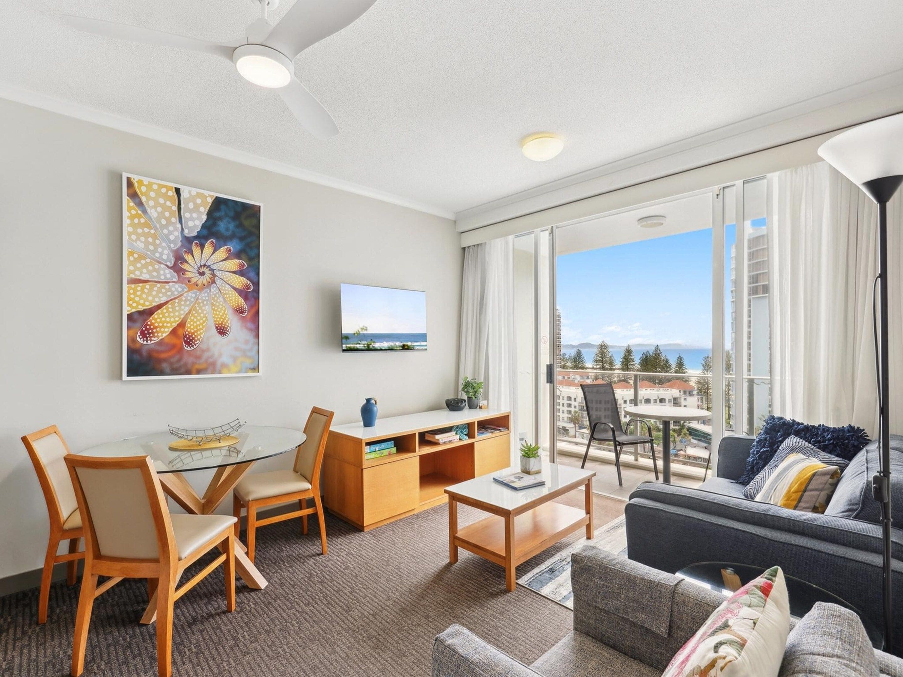 A modern hotel room with a balcony, a dining area, and a living space.