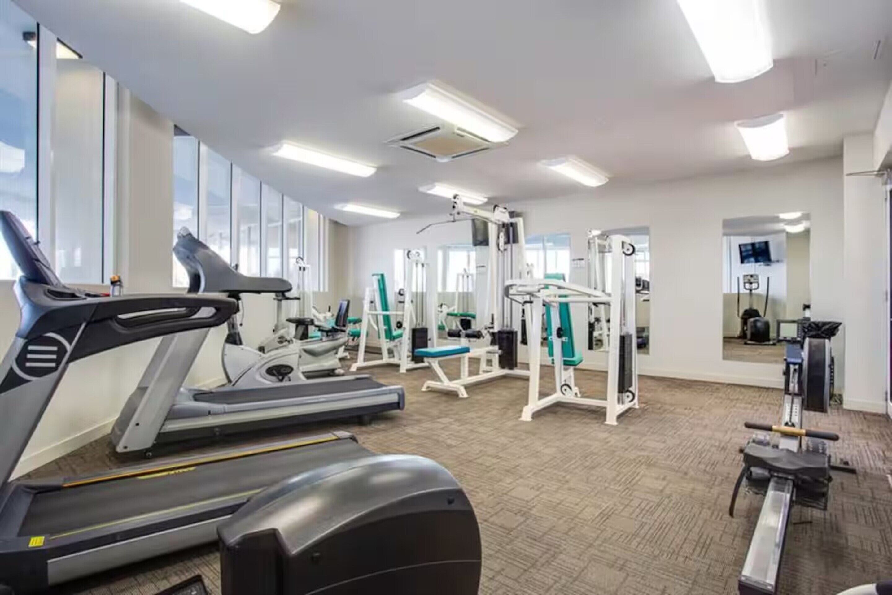 Ein Fitnessstudio mit Laufbändern, Kraftgeräten und Trainingsausrüstung.