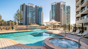 Une piscine avec un jacuzzi, des chaises longues et une terrasse en bois.
