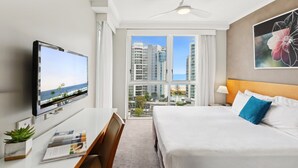 Une chambre d’hôtel équipée d’un lit, d’un bureau, d’une télévision et offrant une vue sur les gratte-ciel.