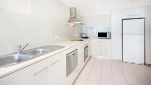 Une cuisine moderne dotée d’appareils électroménagers en acier inoxydable, de meubles blancs et d’un évier à deux bacs.