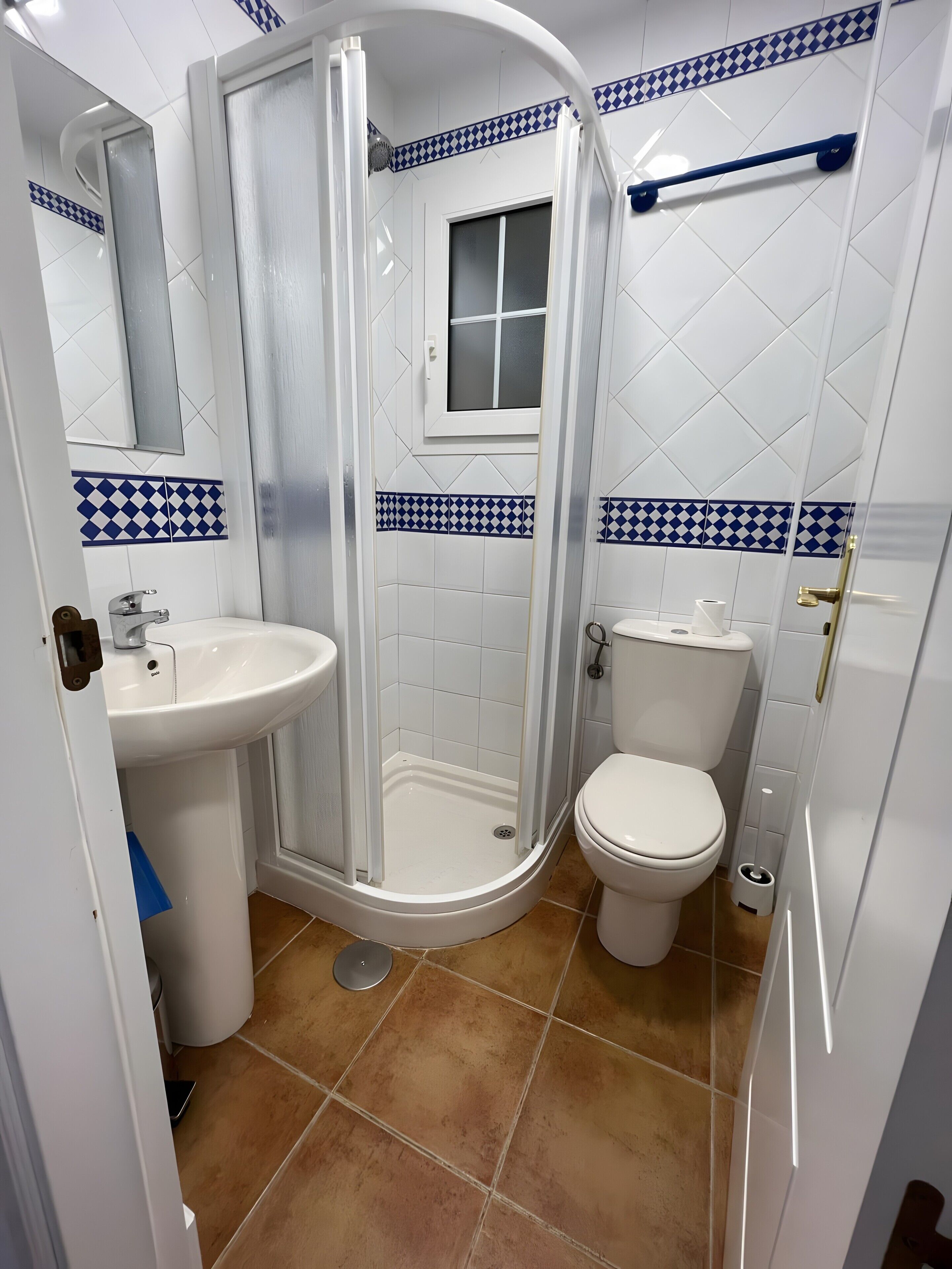 Une salle de bain avec une douche, des toilettes, un lavabo et une fenêtre.