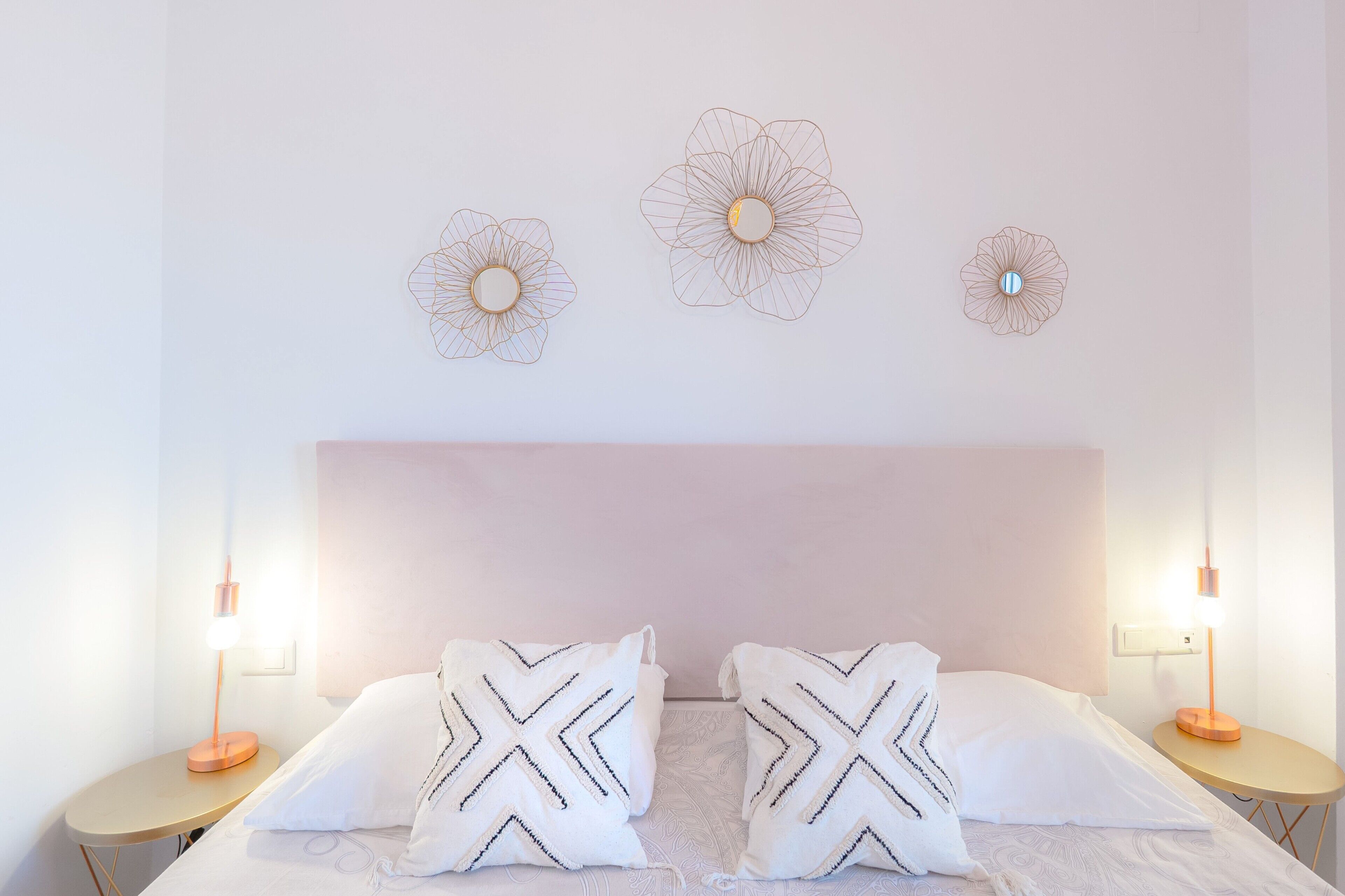 A hotel room with a bed, two nightstands, and three wall-mounted light fixtures.