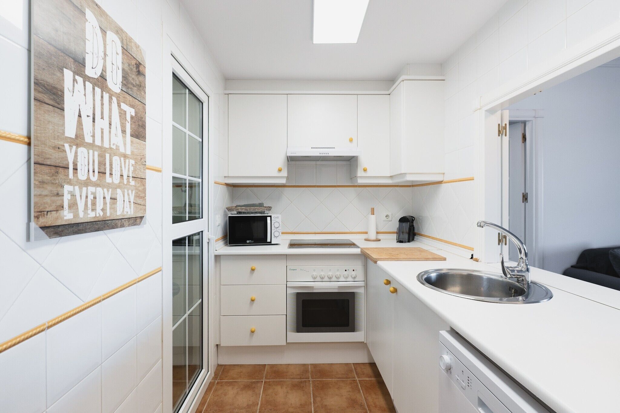A compact kitchen with white cabinetry, a microwave, oven, and a sink.