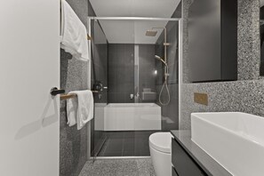 A modern bathroom with a glass-enclosed shower, a standalone bathtub, and a toilet.