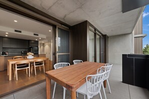 A modern kitchen with dark cabinets, a wooden dining table, and white chairs.