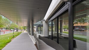 A modern building with a covered walkway, large windows, and a view of the street. - Stylish 2-bed in Braddon With Alfresco Dining (Canberra)