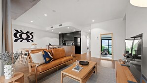A modern living room with a sofa, coffee table, and a dining area. - Stylish 2-bed in Braddon With Alfresco Dining (Canberra)