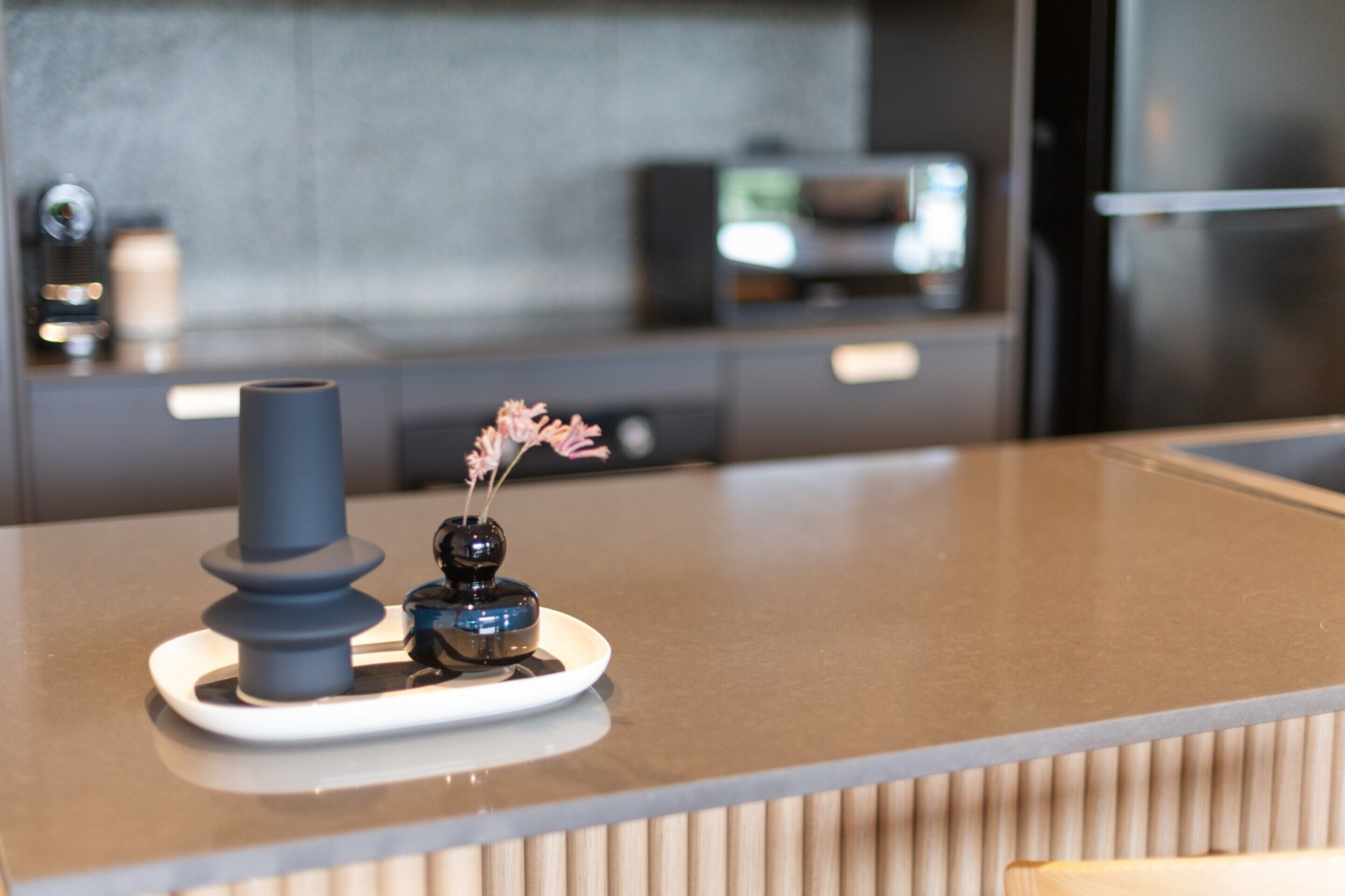 Uma cozinha moderna com bancada elegante, um pequeno vaso decorativo com flores e uma máquina de café.