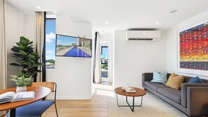 Uma sala moderna com sofá, mesa de centro e um espaço de jantar com mesa e cadeiras.