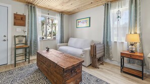 A cozy living room with a wooden ceiling, a sofa, a wooden chest of drawers, and a lamp on a side table. - 🏖️Short Walk to Beach - Perfect for Families - Terrapin Station🏖️ (New Smyrna Beach)