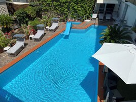 Una piscina al aire libre de temporada, sillones reclinables de piscina