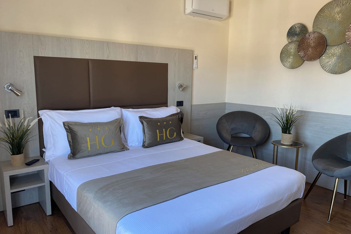 Habitació d'hotel moderna amb un llit gran, taules de nit, una cadira i decoració mural.