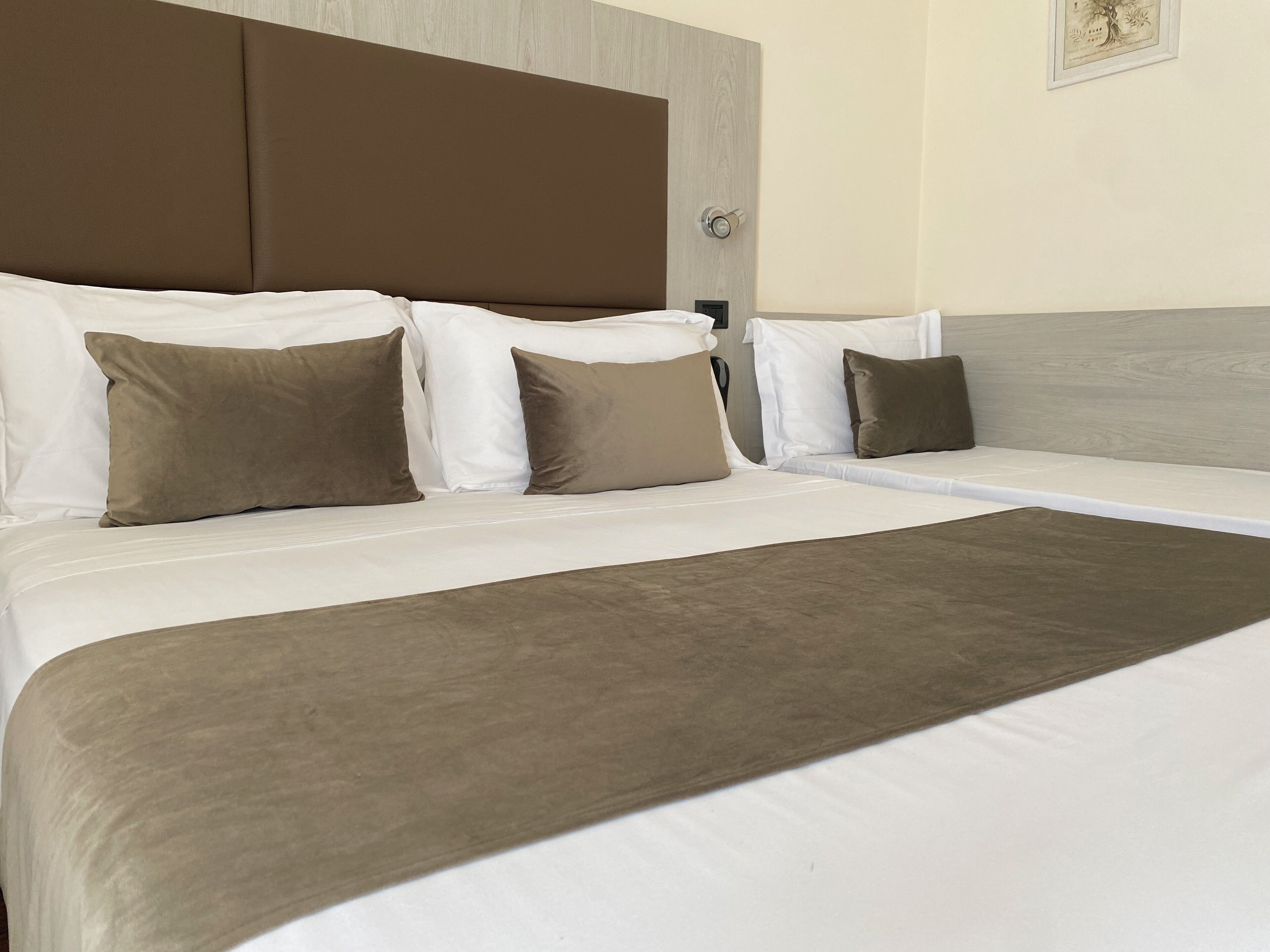 A hotel room with a large bed, brown headboard, and white bedding.