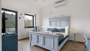 Ein Schlafzimmer mit einem Bett, einem Fenster, einem kleinen Tisch und einer Kommode.