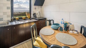Eine Küche mit Fenster, Holdekor, einem runden Esstisch mit Unterlagen und Blick auf eine Landschaft.