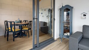 Ein Zimmer mit Esstisch, Stühlen, einer Couch, einem Schrank mit Dekoration und einer Glasschiebetür zu einem anderen Raum.
